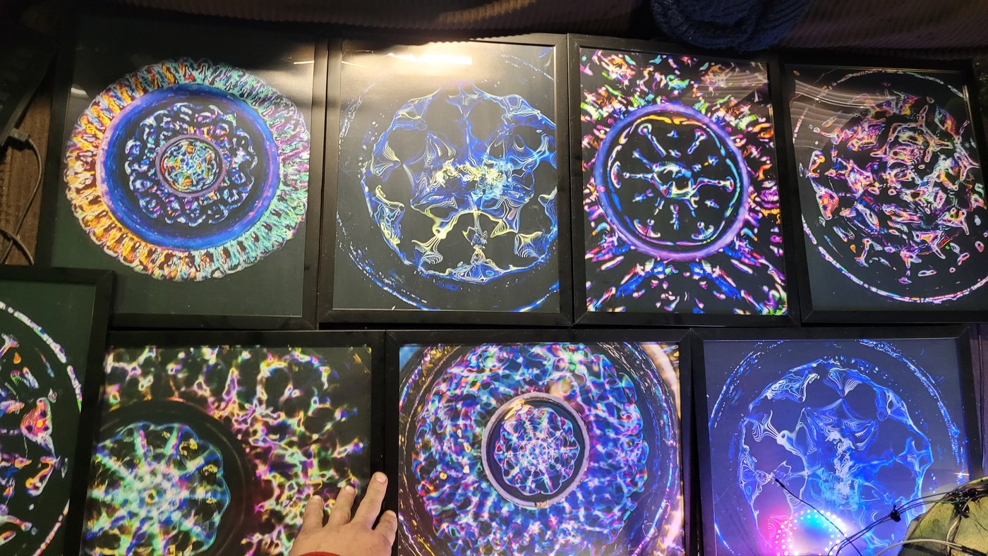 A wall of eight framed cymatics prints leaned together, showing the range of patterns and colors