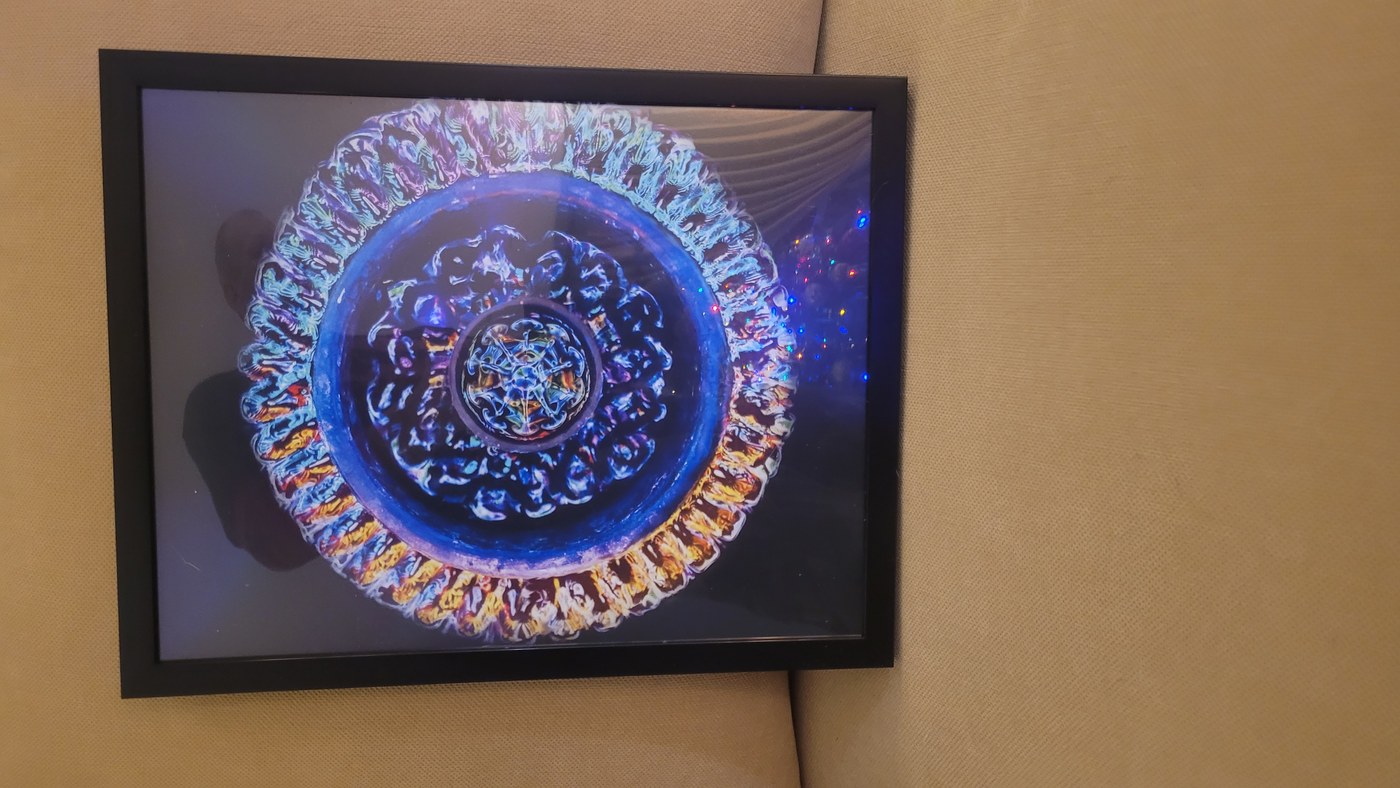 A framed cymatics print displayed at home near string lights