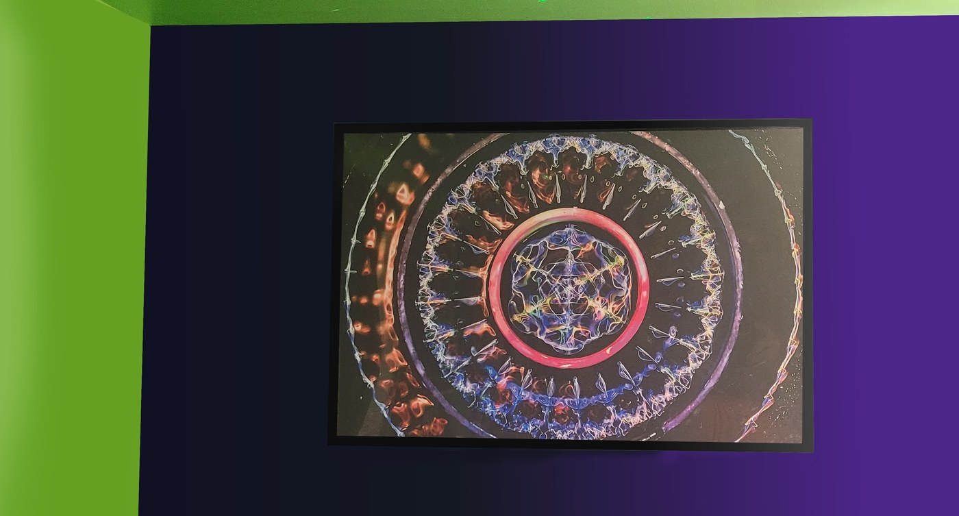 A framed 24 by 36 inch cymatics print hanging on a colorful accent wall
