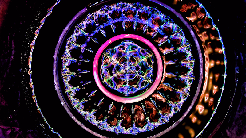 Cymatics Print Gallery — concentric spoked standing-wave mandala in magenta, blue, and amber captured from a fluid cymatics rig